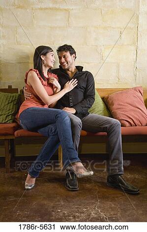 Multiracial couple sitting together on sofa View Large Photo Image Stock Image - Multiracial couple sitting together on sofa. Fotosearch