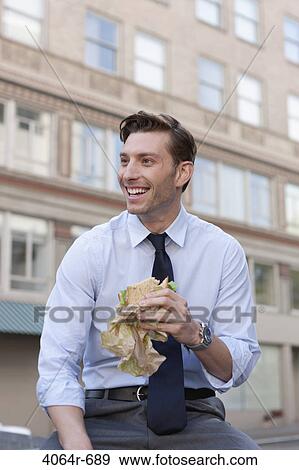 Outdoor portrait of businessman eating sandwich View Large Photo Image Stock Photo - Outdoor portrait of businessman eating sandwich. Fotosearch
