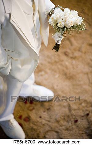 Partial view of a groom in a white tuxedo holding a bouquet of white roses View Large Photo Image Stock Image - Partial view of a groom in a white tuxedo holding a bouquet of white roses. Fotosearch