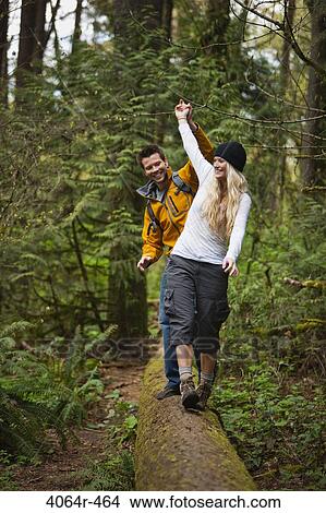 Picture - Portland, Oregon, USA, Couple walking along log in forest. Fotosearch