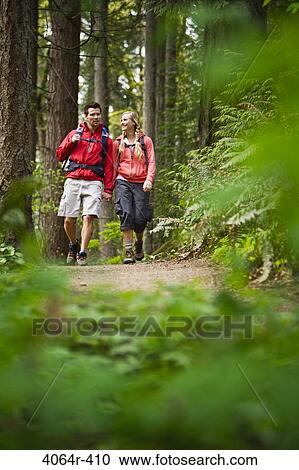 Stock Image - Portland, Oregon, USA, Couple walking on trail through forest. Fotosearch