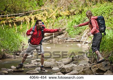 Picture - Portland, Oregon, USA, Man helping woman across creek. Fotosearch