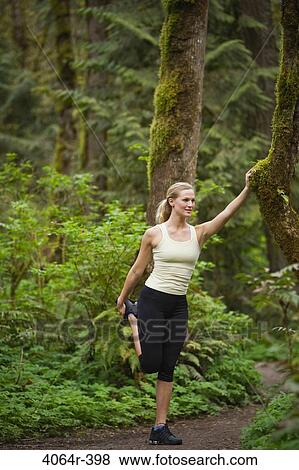 Stock Photo - Portland, Oregon, USA, Woman stretching before run, on trail in forest. Fotosearch
