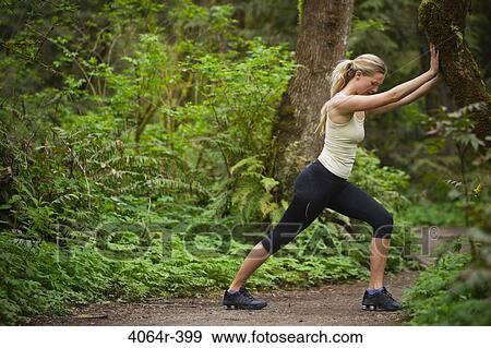 Stock Photo - Portland, Oregon, USA, Woman stretching before run, on trail in forest. Fotosearch