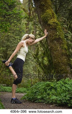 Stock Photograph - Portland, Oregon, USA, Woman stretching before run, on trail in forest. Fotosearch