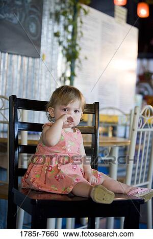 Portrait of a baby girl sitting on a chair View Large Photo Image Stock Image - Portrait of a baby girl sitting on a chair. Fotosearch