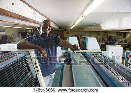 Portrait of a blue-collar man standing behind a printing machine View Large Photo Image Stock Image - Portrait of a blue-collar man standing behind a printing machine. Fotosearch
