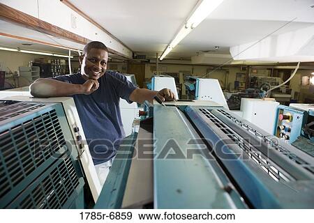 Portrait of a blue-collar man standing behind a printing machine View Large Photo Image Stock Photo - Portrait of a blue-collar man standing behind a printing machine. Fotosearch