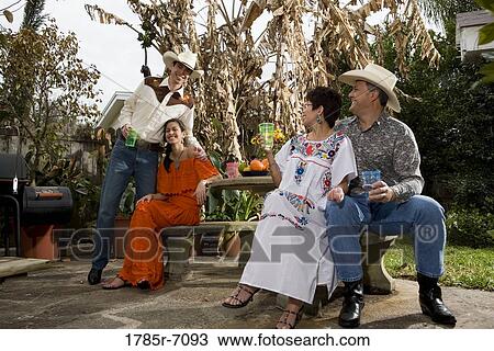 Stock Image - Portrait of a cheerful Tex-Mex family sitting together in the backyard of house. Fotosearch