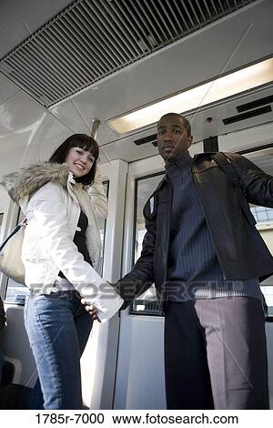 Portrait of a cheerful young inter-racial couple traveling in a mass transit train View Large Photo Image Stock Image - Portrait of a cheerful young inter-racial couple traveling in a mass transit train. Fotosearch