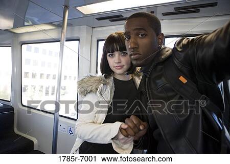 Portrait of a cheerful young inter-racial couple traveling in a mass transit train View Large Photo Image Stock Image - Portrait of a cheerful young inter-racial couple traveling in a mass transit train. Fotosearch