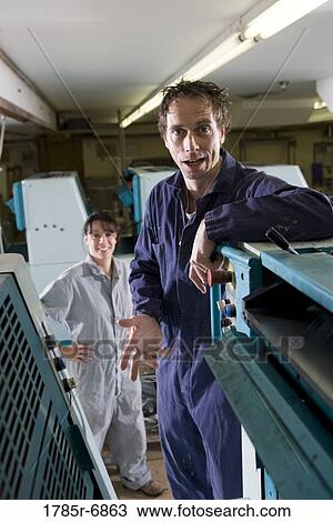 Portrait of a man and a woman in coveralls behind a printing machine View Large Photo Image Stock Image - Portrait of a man and a woman in coveralls behind a printing machine. Fotosearch