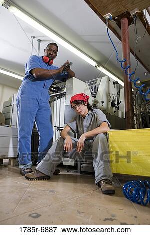 Portrait of a man and a woman in coveralls next to some machinery View Large Photo Image Stock Photo - Portrait of a man and a woman in coveralls next to some machinery. Fotosearch