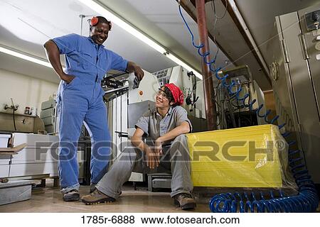 Portrait of a man and a woman in coveralls next to some machinery View Large Photo Image Stock Photo - Portrait of a man and a woman in coveralls next to some machinery. Fotosearch