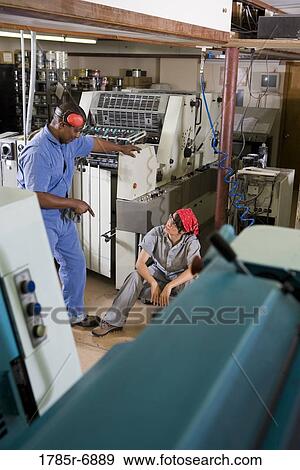 Portrait of a man and a woman in coveralls next to some machinery View Large Photo Image Stock Photo - Portrait of a man and a woman in coveralls next to some machinery. Fotosearch