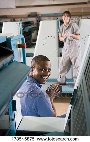 Portrait of a man and a woman in coveralls behind a printing machine View Large Photo Image Stock Photography - Portrait of a man and a woman in coveralls behind a printing machine. Fotosearch