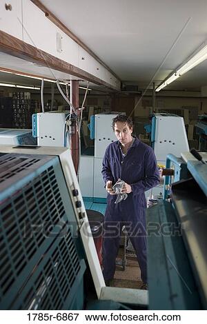 Portrait of a man in coveralls behind a printing machine View Large Photo Image Stock Photo - Portrait of a man in coveralls behind a printing machine. Fotosearch