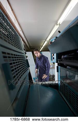 Portrait of a man in coveralls behind a printing machine View Large Photo Image Stock Photo - Portrait of a man in coveralls behind a printing machine. Fotosearch