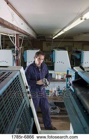 Portrait of a man in coveralls behind a printing machine View Large Photo Image Stock Photograph - Portrait of a man in coveralls behind a printing machine. Fotosearch