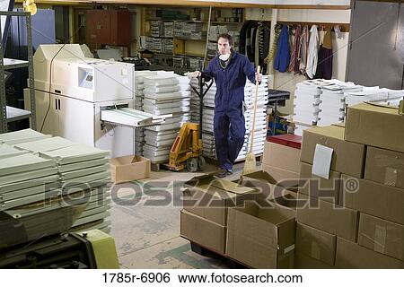 Portrait of a man in coveralls holding a broom in a warehouse View Large Photo Image Stock Photograph - Portrait of a man in coveralls holding a broom in a warehouse. Fotosearch