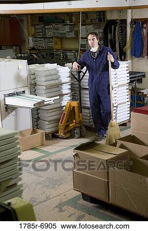 Portrait of a man in coveralls holding a broom in a warehouse View Large Photo Image Stock Photography - Portrait of a man in coveralls holding a broom in a warehouse. Fotosearch