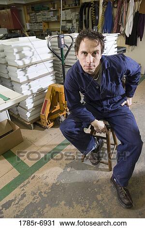 Portrait of a man sitting on a stool in a warehouse View Large Photo Image Stock Image - Portrait of a man sitting on a stool in a warehouse. Fotosearch