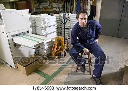Portrait of a man sitting on a stool in a warehouse View Large Photo Image Stock Image - Portrait of a man sitting on a stool in a warehouse. Fotosearch