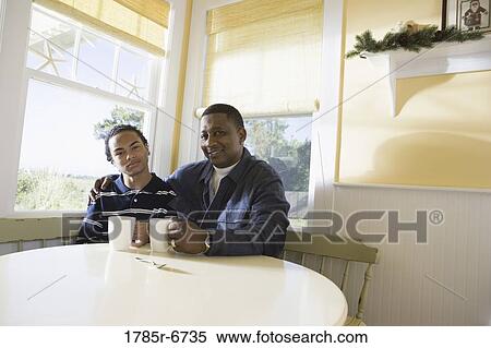 Portrait of a man sitting with his son at kitchen table View Large Photo Image Stock Photography - Portrait of a man sitting with his son at kitchen table. Fotosearch