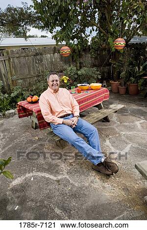 Portrait of a mature man sitting in front of a picnic table View Large Photo Image Stock Image - Portrait of a mature man sitting in front of a picnic table. Fotosearch