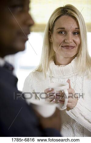 Portrait of a mature woman holding coffee mug looking at man in foreground View Large Photo Image Stock Photograph - Portrait of a mature woman holding coffee mug looking at man in foreground. Fotosearch