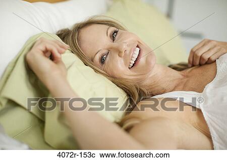 Portrait of a mature woman lying on the bed and smiling View Large Photo Image Stock Image - Portrait of a mature woman lying on the bed and smiling. Fotosearch
