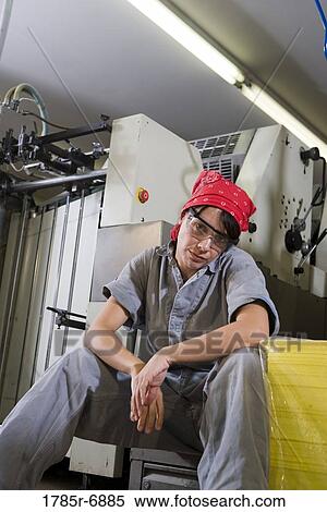Portrait of a tired woman in coveralls sitting next to some machinery View Large Photo Image Stock Photography - Portrait of a tired woman in coveralls sitting next to some machinery. Fotosearch