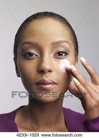 Portrait of a woman applying moisturizer on face View Large Photo Image Stock Photo - Portrait of a woman applying moisturizer on face. Fotosearch