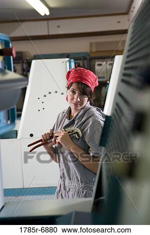 Portrait of a woman in coveralls and holding a wrench standing in front of a printing machine View Large Photo Image Stock Image - Portrait of a woman in coveralls and holding a wrench standing in front of a printing machine. Fotosearch