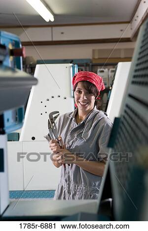 Portrait of a woman in coveralls and holding a wrench standing in front of a printing machine View Large Photo Image Stock Image - Portrait of a woman in coveralls and holding a wrench standing in front of a printing machine. Fotosearch