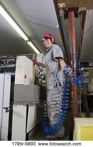 Portrait of a woman in coveralls and safety gear operating a machine View Large Photo Image Stock Image - Portrait of a woman in coveralls and safety gear operating a machine. Fotosearch