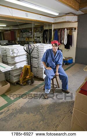 Portrait of a woman sitting on a stool in a warehouse View Large Photo Image Stock Photo - Portrait of a woman sitting on a stool in a warehouse. Fotosearch