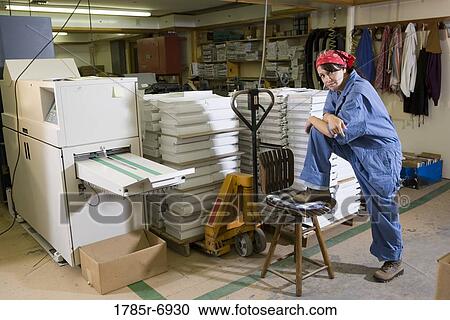 Portrait of a woman standing next to a stool in a warehouse View Large Photo Image Stock Image - Portrait of a woman standing next to a stool in a warehouse. Fotosearch