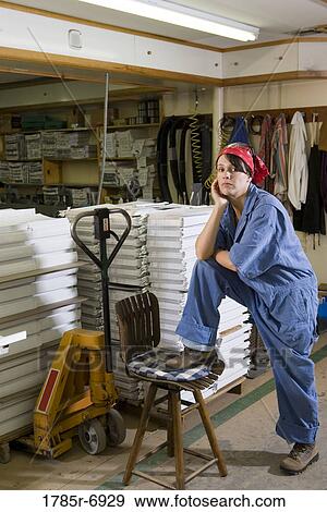 Portrait of a woman standing next to a stool in a warehouse View Large Photo Image Stock Photo - Portrait of a woman standing next to a stool in a warehouse. Fotosearch