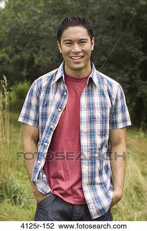 Stock Image - Portrait of a young man smiling in a field. Fotosearch