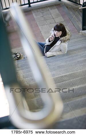 Portrait of a young woman at the bottom of a flight of stairs and on a cell phone View Large Photo Image Stock Photography - Portrait of a young woman at the bottom of a flight of stairs and on a cell phone. Fotosearch