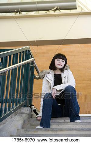 Portrait of a young woman sitting at the top of a concrete staircase View Large Photo Image Stock Image - Portrait of a young woman sitting at the top of a concrete staircase. Fotosearch