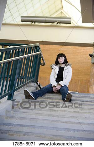 Portrait of a young woman sitting at the top of a concrete staircase View Large Photo Image Stock Image - Portrait of a young woman sitting at the top of a concrete staircase. Fotosearch