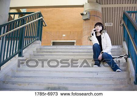 Portrait of a young woman sitting at the top of a concrete staircase on cellphone View Large Photo Image Stock Image - Portrait of a young woman sitting at the top of a concrete staircase on cellphone. Fotosearch