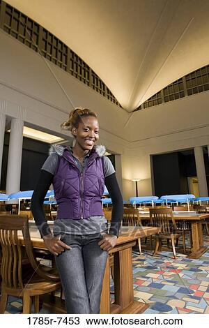 Portrait of a young woman standing in the reading room of a library View Large Photo Image Stock Image - Portrait of a young woman standing in the reading room of a library. Fotosearch