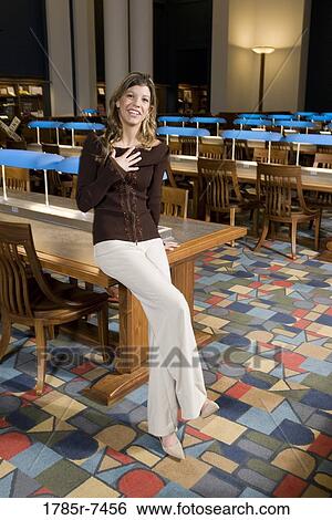 Portrait of a young woman standing in the reading room of a library View Large Photo Image Stock Photograph - Portrait of a young woman standing in the reading room of a library. Fotosearch