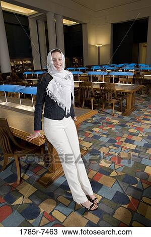 Portrait of a young woman wearing a head scarf standing in the reading room of a library View Large Photo Image Stock Image - Portrait of a young woman wearing a head scarf standing in the reading room of a library. Fotosearch