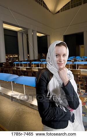 Portrait of a young woman wearing a head scarf standing in the reading room of a library View Large Photo Image Stock Photography - Portrait of a young woman wearing a head scarf standing in the reading room of a library. Fotosearch