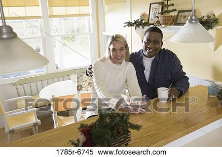 Portrait of an inter-racial couple with coffee mugs sitting at a kitchen counter View Large Photo Image Stock Photography - Portrait of an inter-racial couple with coffee mugs sitting at a kitchen counter. Fotosearch