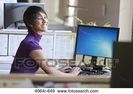 Stock Photo - Portrait of businesswoman using computer at office desk. Fotosearch